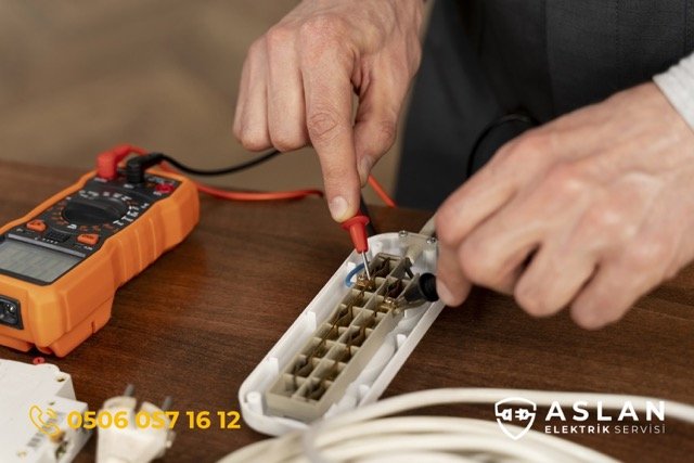 Şifne'de priz tamiri yapmak için elektrik ölçümü yapan bir elektrikçi